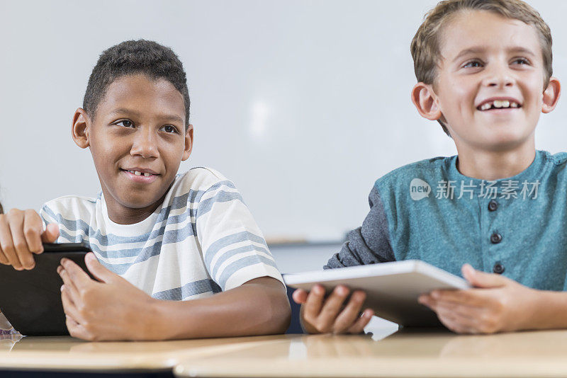 两个男生在课堂上玩平板电脑