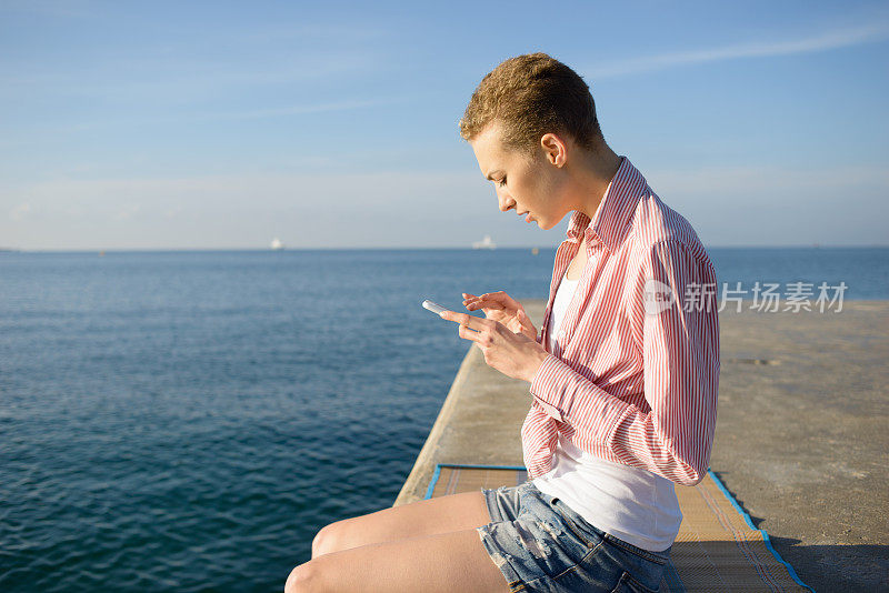 夏日黎明坐在海边使用智能手机