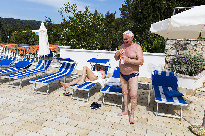 老夫妇在泳池边享受日光浴