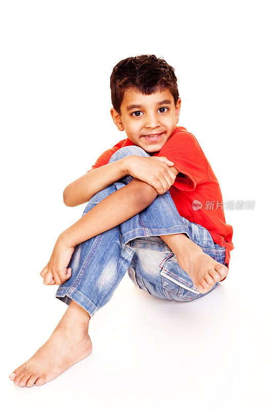 一个随意的印第安小男孩孤立地坐在白色上