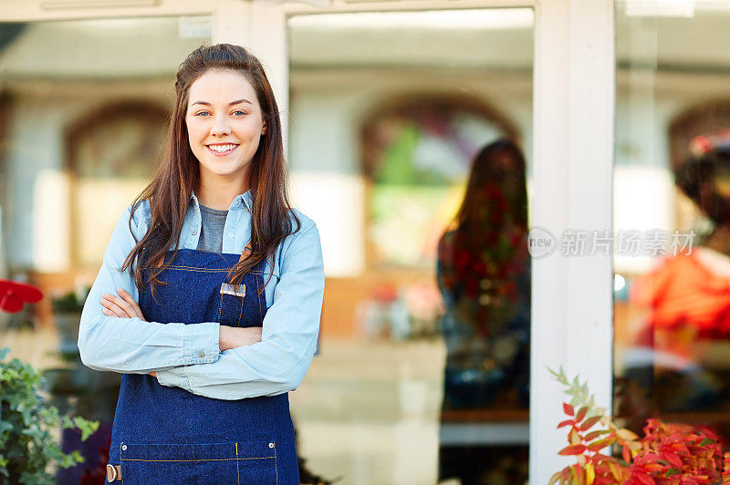 自信的花店老板双手交叉站在店门口