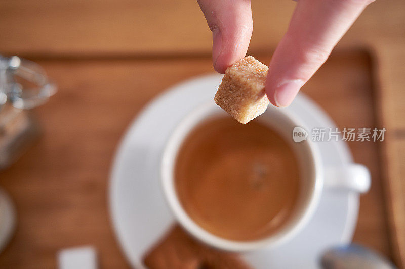 手和方糖放在咖啡杯上