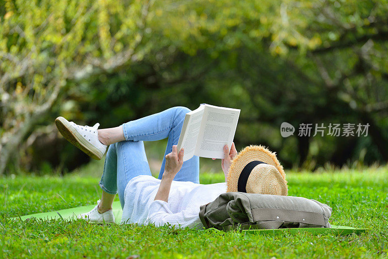 女人躺在绿色的草地上看书
