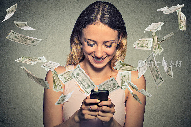 快乐的女人使用智能手机，钞票从屏幕上飞出