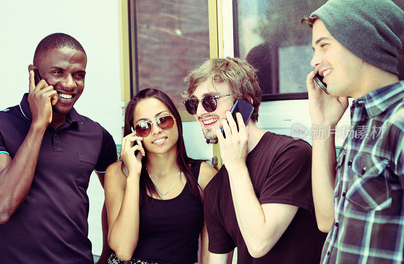 准备好了吗?四个时髦的年轻人用手机聊天