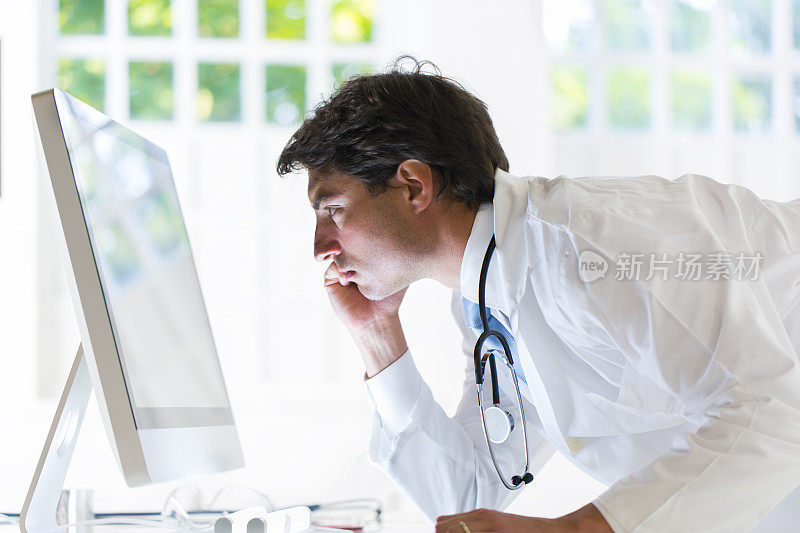 男医生扬用听诊器看着电脑显示器