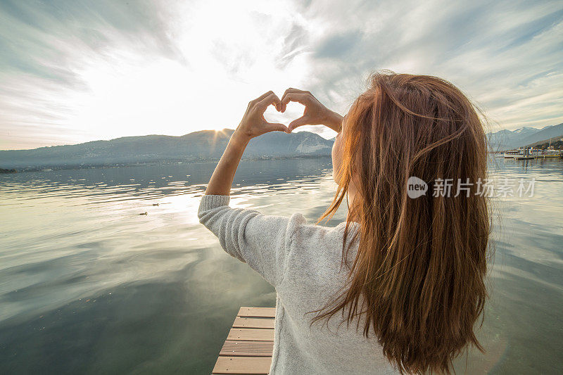 湖上码头上的女人做了心形的指架