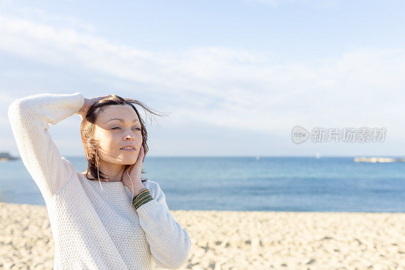 年轻女子在海滩上戴着耳机听音乐