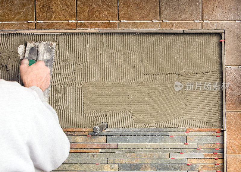 瓷砖工人正在为厨房后挡板擦砂浆