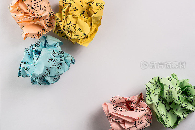 皱巴巴的彩色纸球，上面写着数学方程式，放在皱巴巴的纸上