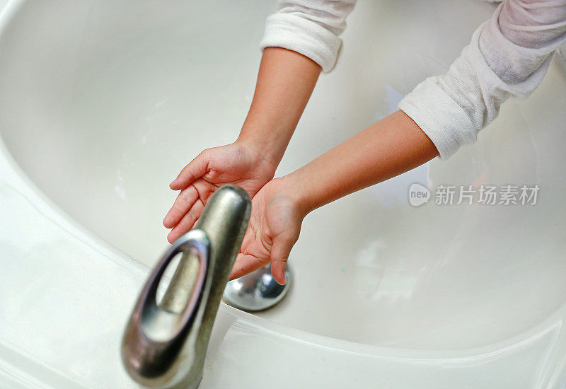 一个孩子的手在水龙头下的水。洗手。