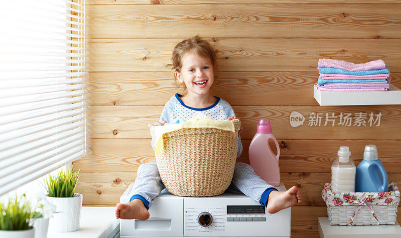 快乐的家庭主妇孩子女孩在洗衣机洗衣机