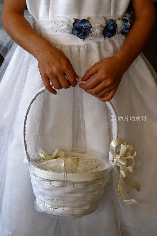 一个穿着白色裙子的花童的特写