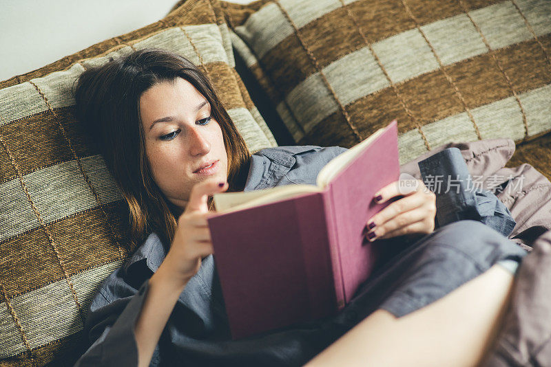 躺在床上看她最喜欢的书的女人。