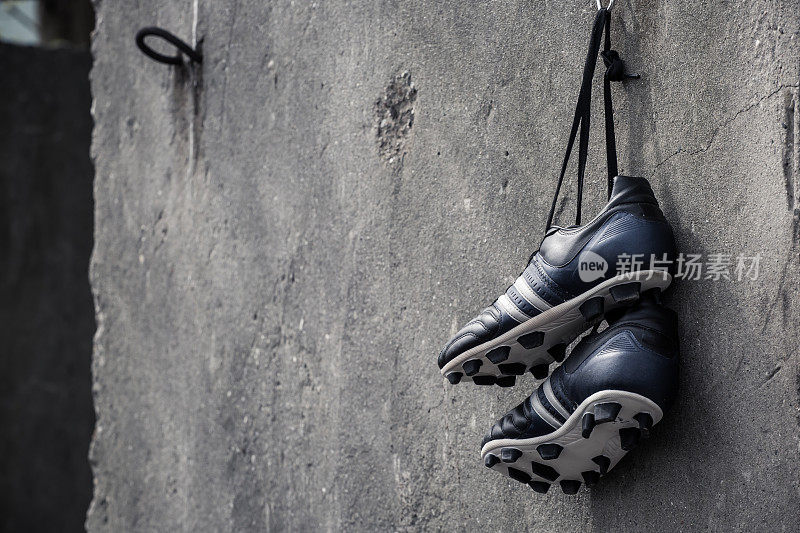 足球鞋挂在粗糙的混凝土墙上。