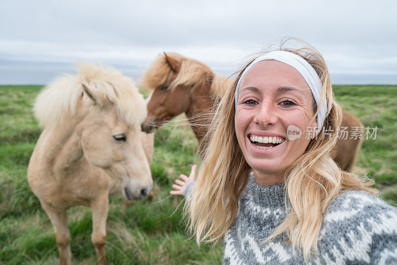 年轻女子在草地上与冰岛马自拍