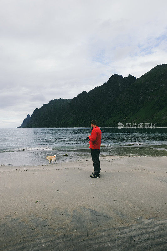 一名男子在挪威的海滩上遛狗