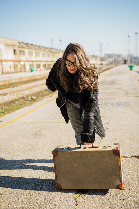 独自行走的年轻女孩提着行李在火车站等待火车