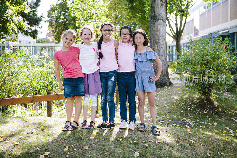 一个女孩团体的肖像在学校花园在夏天，拥抱