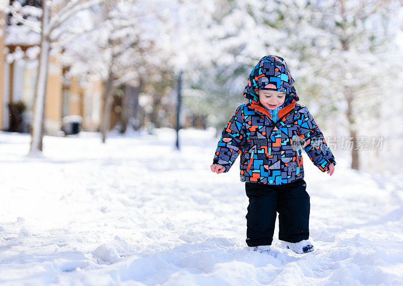 快乐的蹒跚学步的孩子独自行走在雪地里