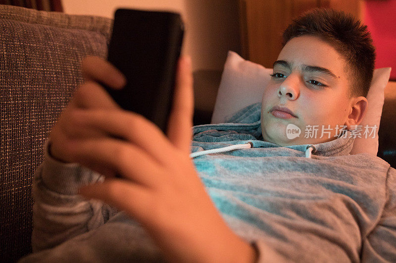 青少年躺在沙发上用手机和朋友聊天，社交网络