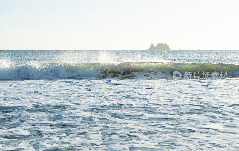 清晨的阳光透过新西兰海滩上的碎浪