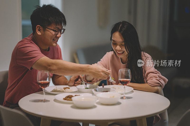 周末，一对亚洲华人夫妇在家里用红酒和中国菜共进晚餐