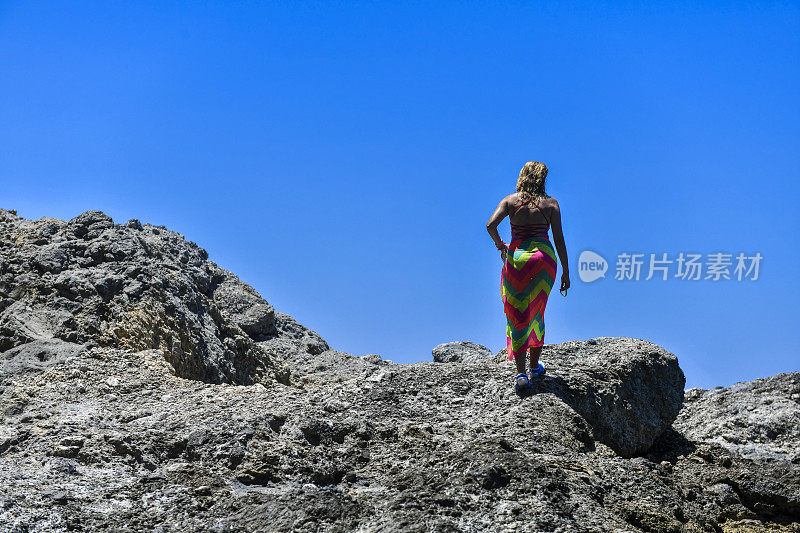 在岩石顶端的女人望着大海。