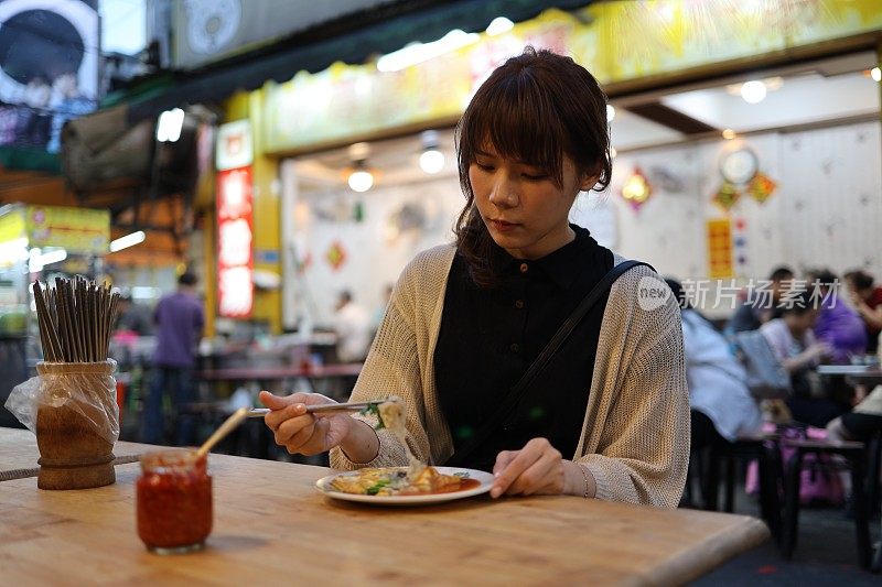 年轻女子在夜市享受美食