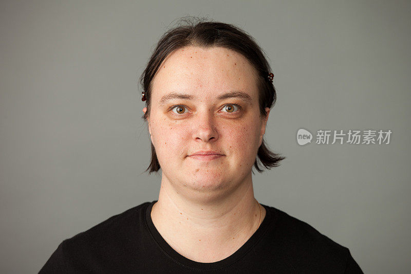 一个35岁的妇女在一个灰色背景的黑色t恤的工作室肖像
