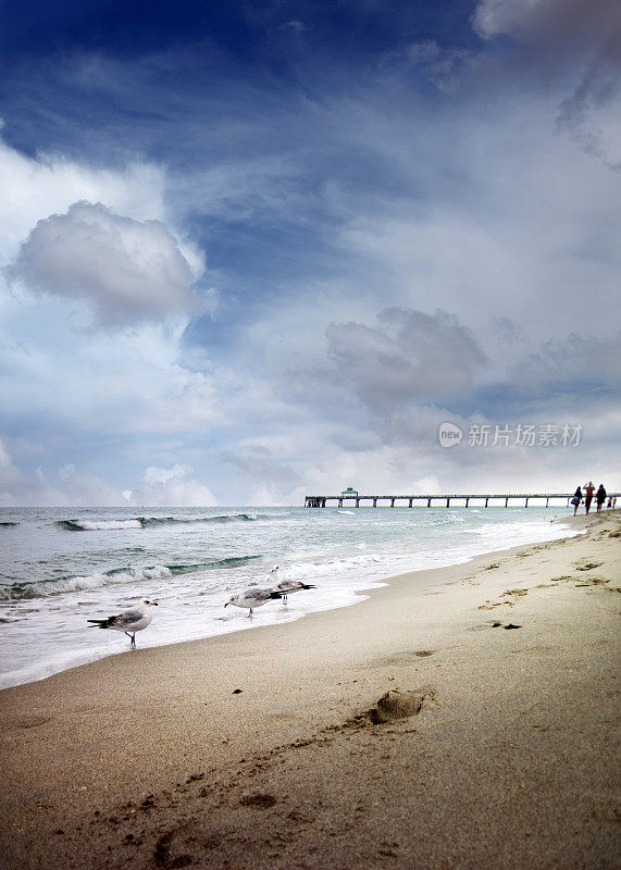 有沙滩和钓鱼码头的海景在暴风雨的天空