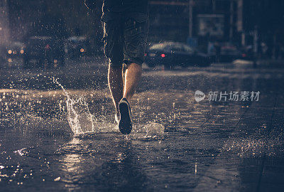 后视图，不认识的人跑在街上在雨天。