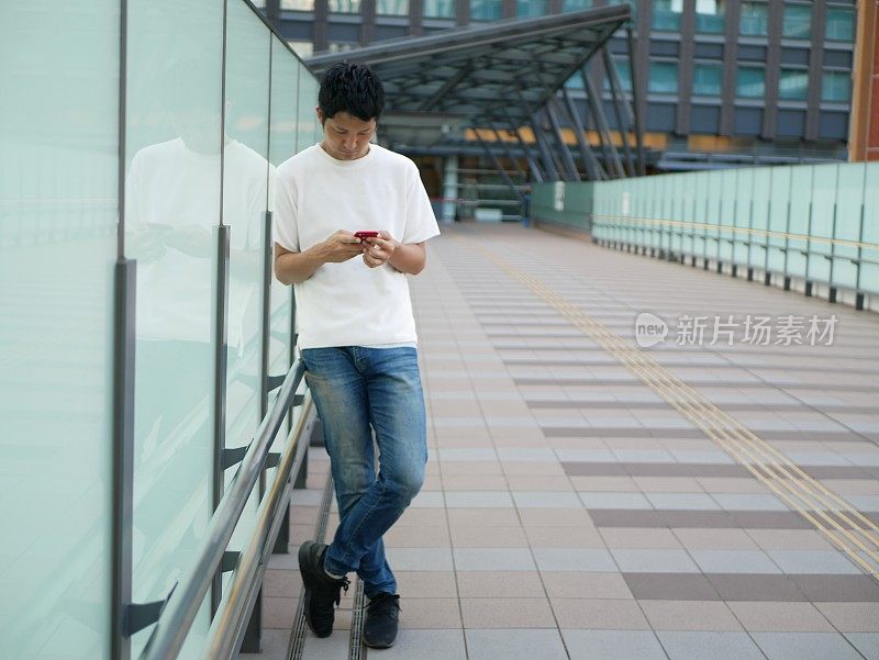 一名成年日本男子正在街上使用智能手机。