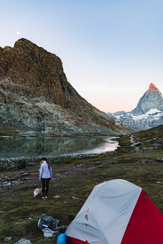 女人和狗遇到日出附近美丽的山湖马特洪峰在瑞士阿尔卑斯山