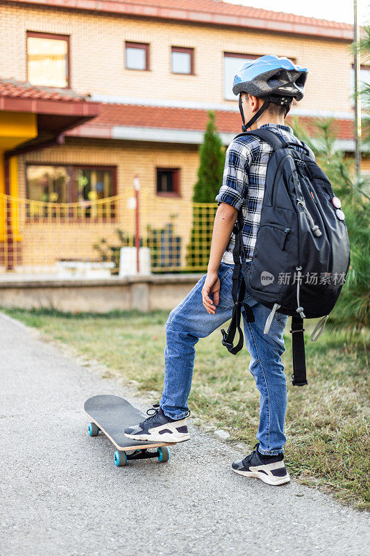 男小学生踩着滑板上学