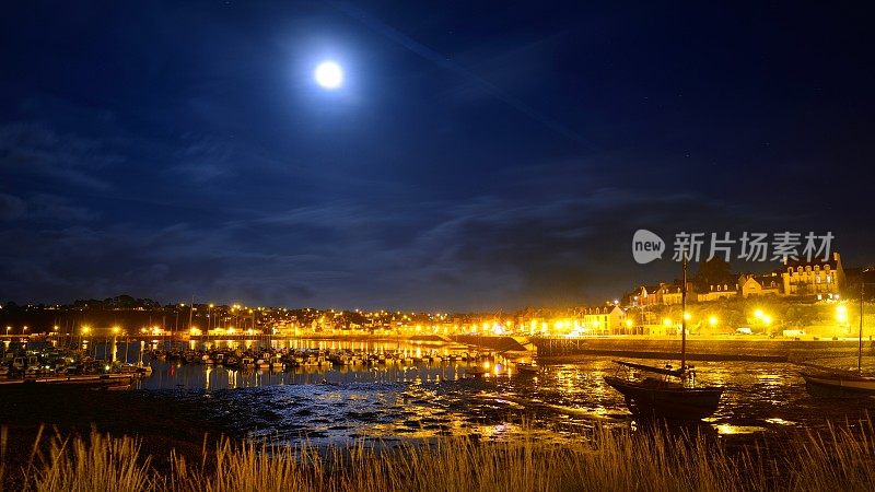 法国卡玛莱滨海港口的午夜景象，停泊着一排排游艇，橙色的灯笼和满月