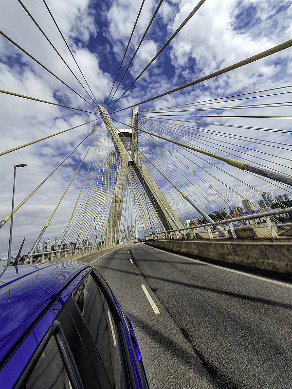 一辆蓝色的汽车从圣保罗市的斜拉桥下驶过。