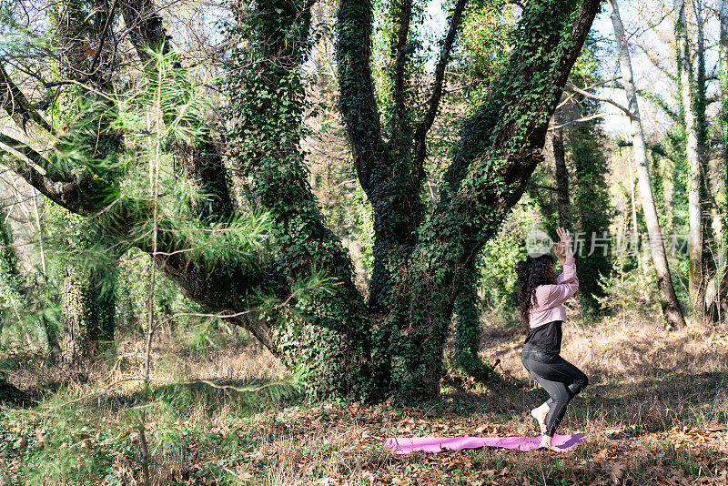成年妇女在丛林中做瑜伽练习的照片