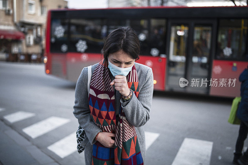 戴着口罩的妇女站在镇上咳嗽