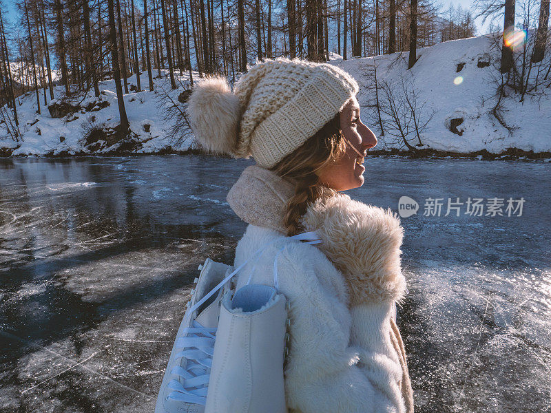 一个年轻女子肩上扛着冰鞋走在结冰的湖面上