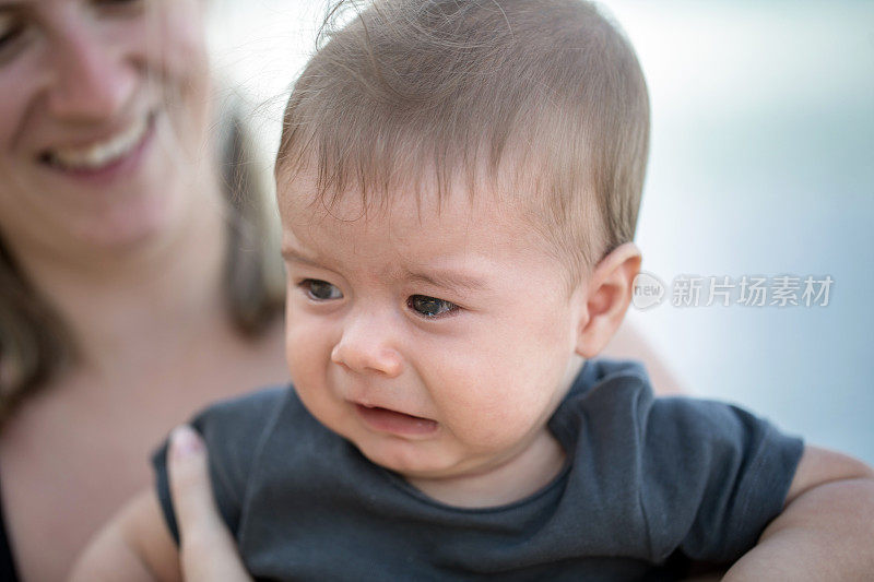 婴儿在妈妈的手中哭泣