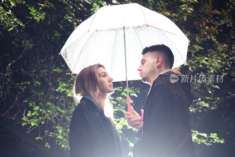 雨夜，一对年轻夫妇站在伞下