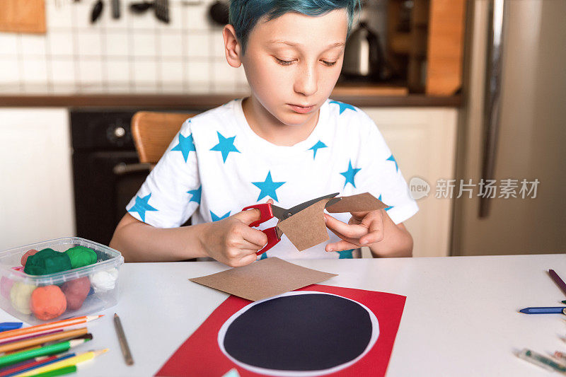 男孩剪纸和制作手工卡片。孩子们艺术和手工艺。