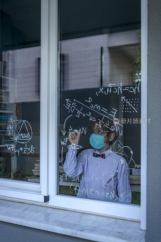戴着口罩的天才男孩在窗户上写公式。