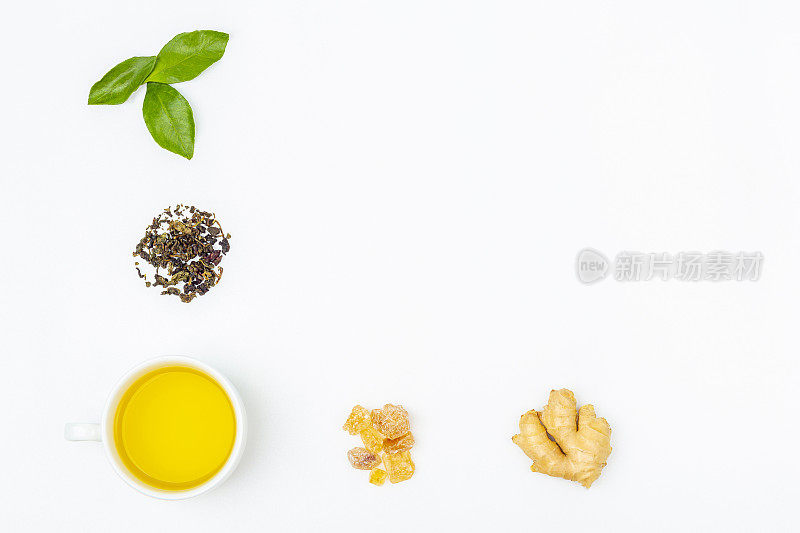 摆放一杯鲜叶乌龙茶，堆干绿茶，糖和生姜在白色的背景，复制文字空间。有机草本，亚洲绿茶茶道。平躺