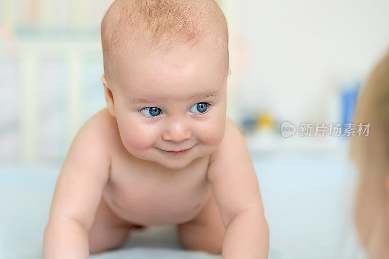 可爱可爱的5个月大的白人小男婴躺在育婴室的床上和姐姐玩耍。快乐健康的新生儿概念。有趣的幼儿肖像