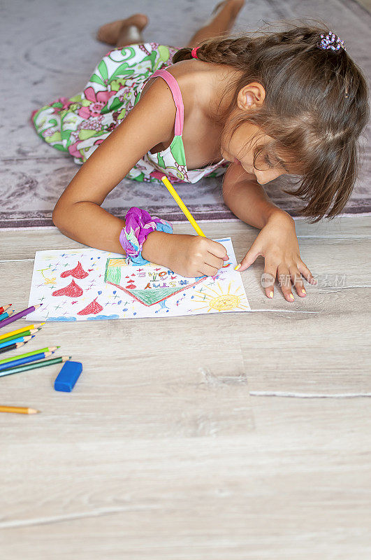 可爱的小女孩在家画画，在纸上写着“呆在家里”的话