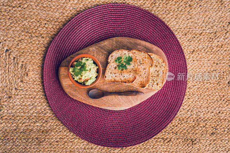 新鲜的自制鳄梨酱和无谷蛋白面包放在木砧板上