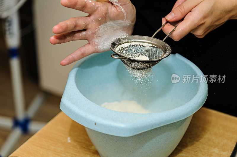 一个女厨师把面粉倒进碗里以便做一个面团的特写照片。