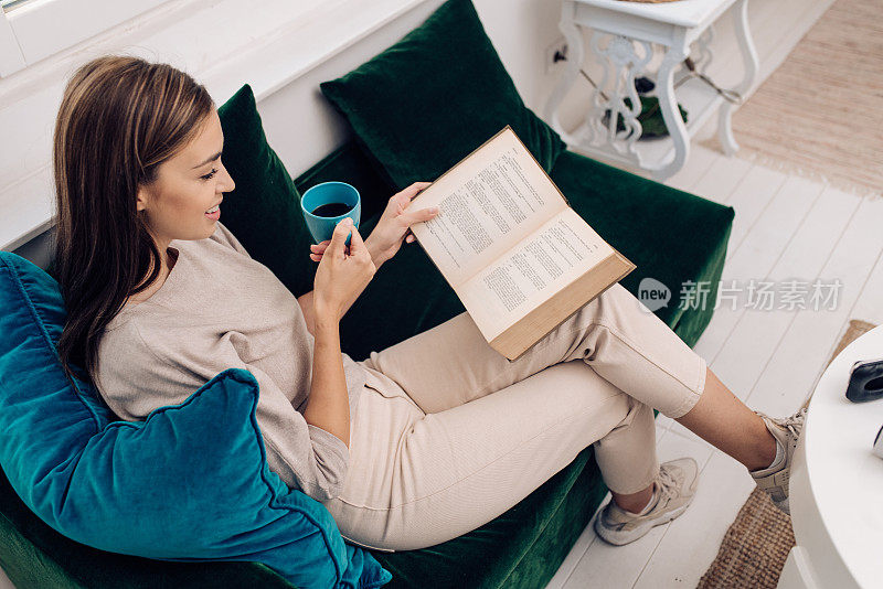 快乐的年轻女子，在家里享受咖啡和阅读